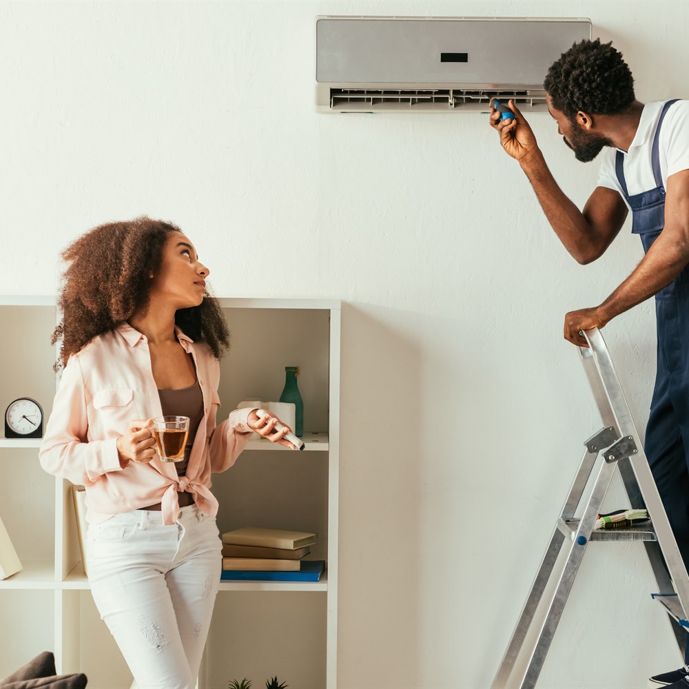 Woman watching repairman working on air conditioner