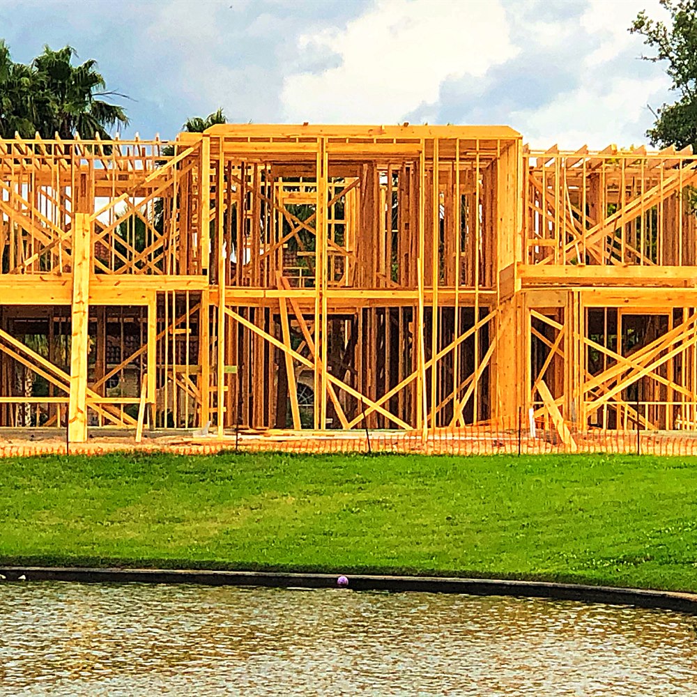Wooden house construction frame beside a pond