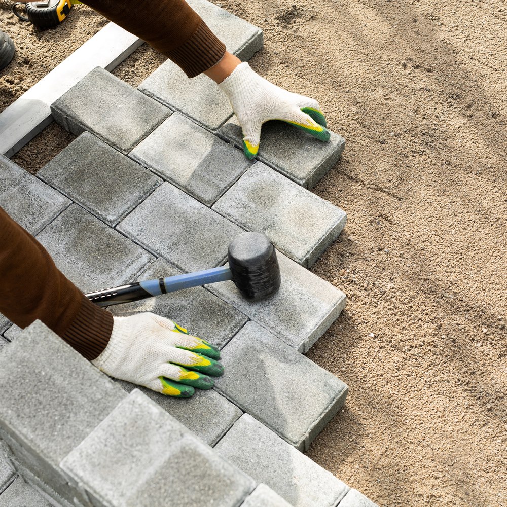 Worker laying concrete pavers for outdoor surface