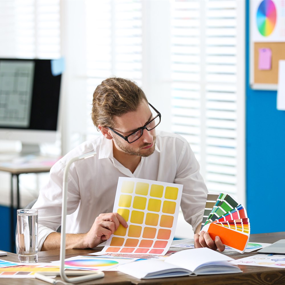 Young man designs with color palette at desk